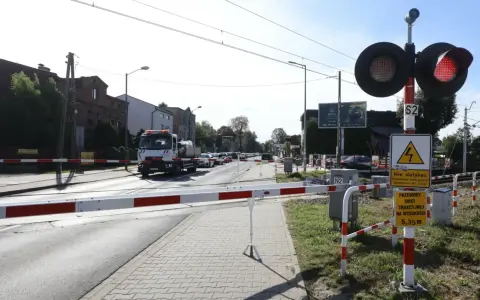 Przejazd kolejowy z zaporami i czerwonymi światłami. Samochód ciężarowy czeka na przejazd.