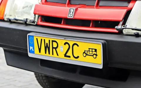 Czerwony grill z logo, reflektor i żółta tablica rejestracyjna z napisem VWR 2C oraz symbolem starego samochodu. To jest rejestracja dw.
