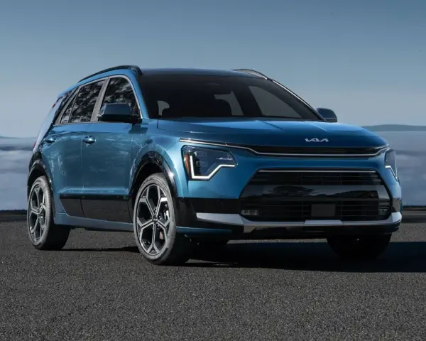 Niebieski Kia Niro Hybrid z nowoczesnym designem, zaparkowany na tle mglistego krajobrazu.