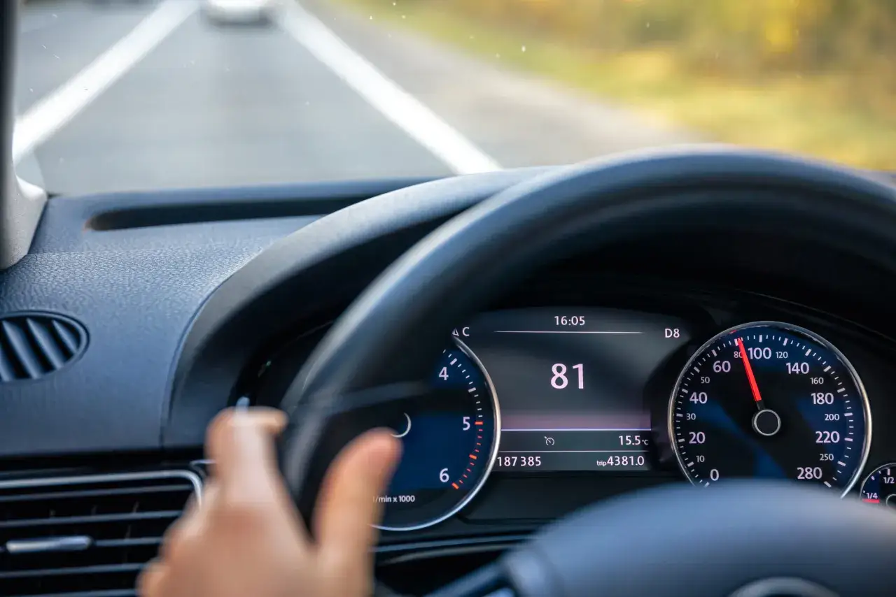 Widok na deskę rozdzielczą samochodu z włączonym tempomatem. Prędkość wynosi 81 km/h.