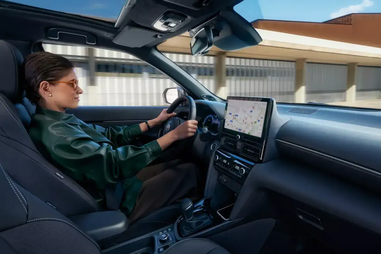 Kobieta prowadzi nowoczesny Toyota Yaris Cross Hybrid, korzystając z nawigacji na dużym ekranie.