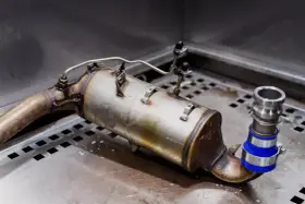 Metalowy element układu wydechowego, prawdopodobnie zawór EGR, leży na metalowej powierzchni.